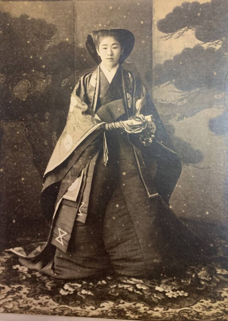 1908年に撮影された曽祖母の花嫁姿。松の金屏風の前で、おすべらかしの髪型に重厚な和装をまとい、袙扇を持つ