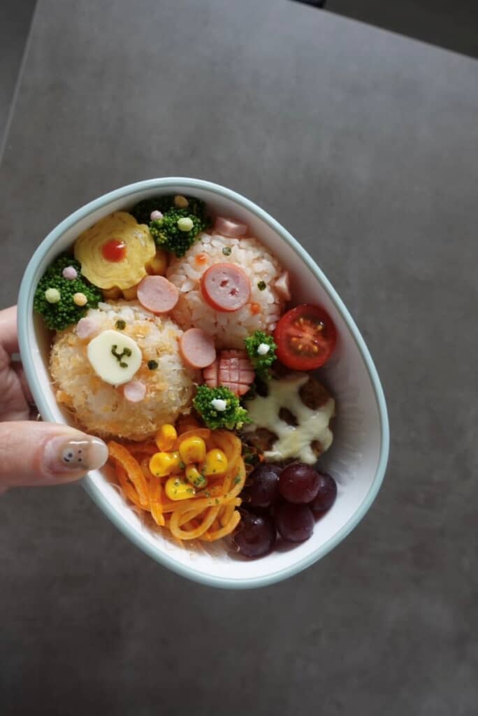 ブタさんの顔が付いたおにぎりとナポリタン、チーズハンバーグが美味しそう