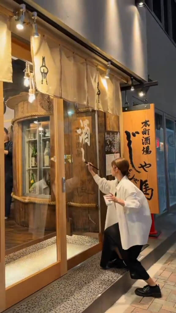 新たにオープンした居酒屋で書のライブパフォーマンスをする梨乃さん