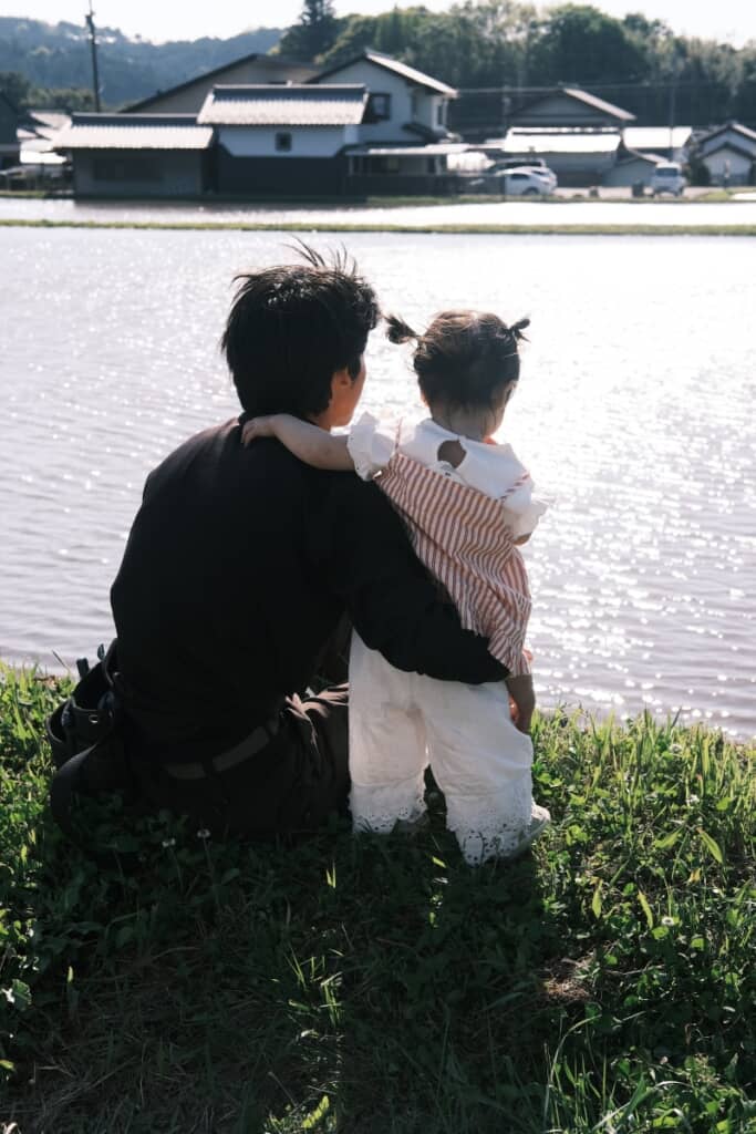 パパさんの首に腕を回して一緒に川を見ています