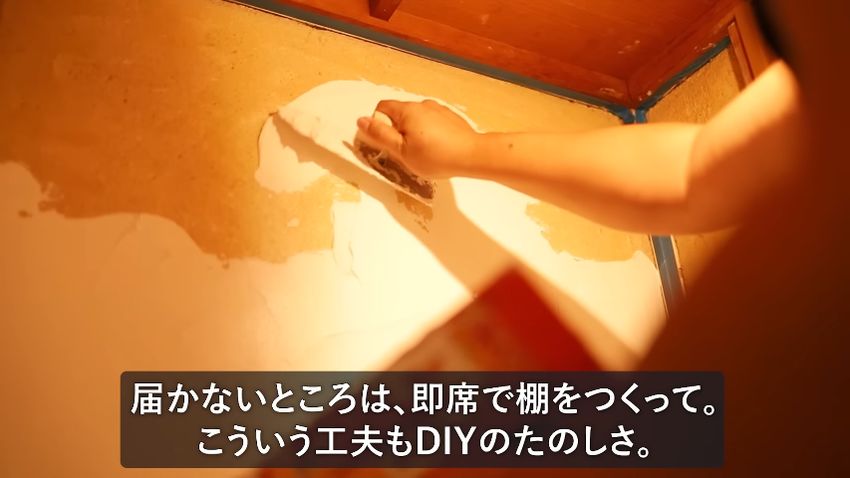 即席で作った台に乗り、高い位置にしっくいを塗る