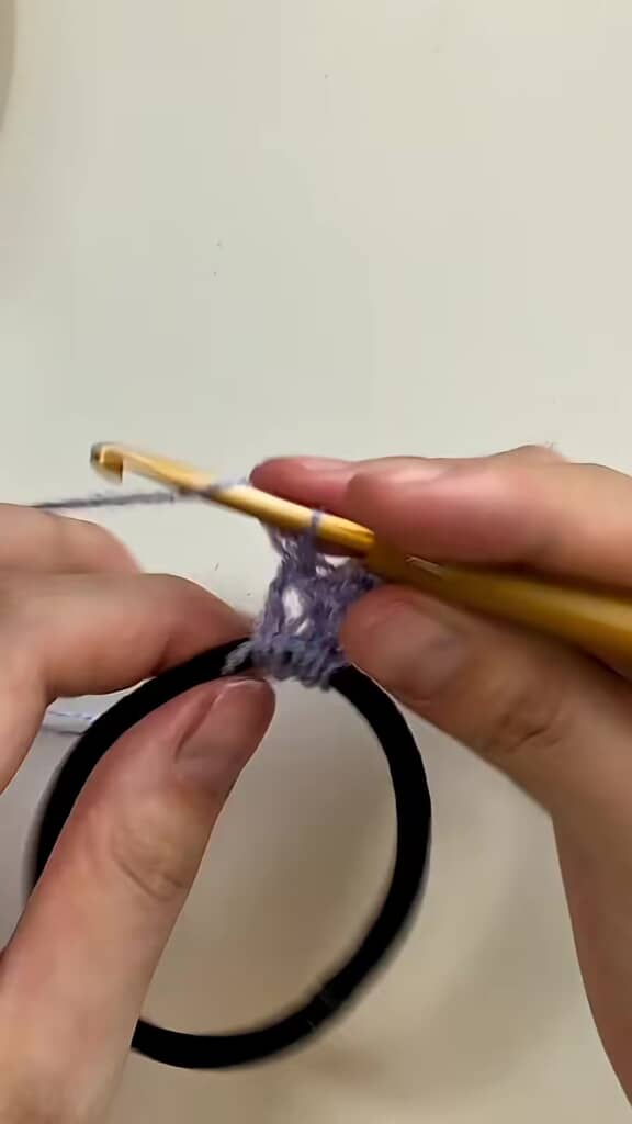 ヘアゴムに毛糸を長編みで編み込む様子
