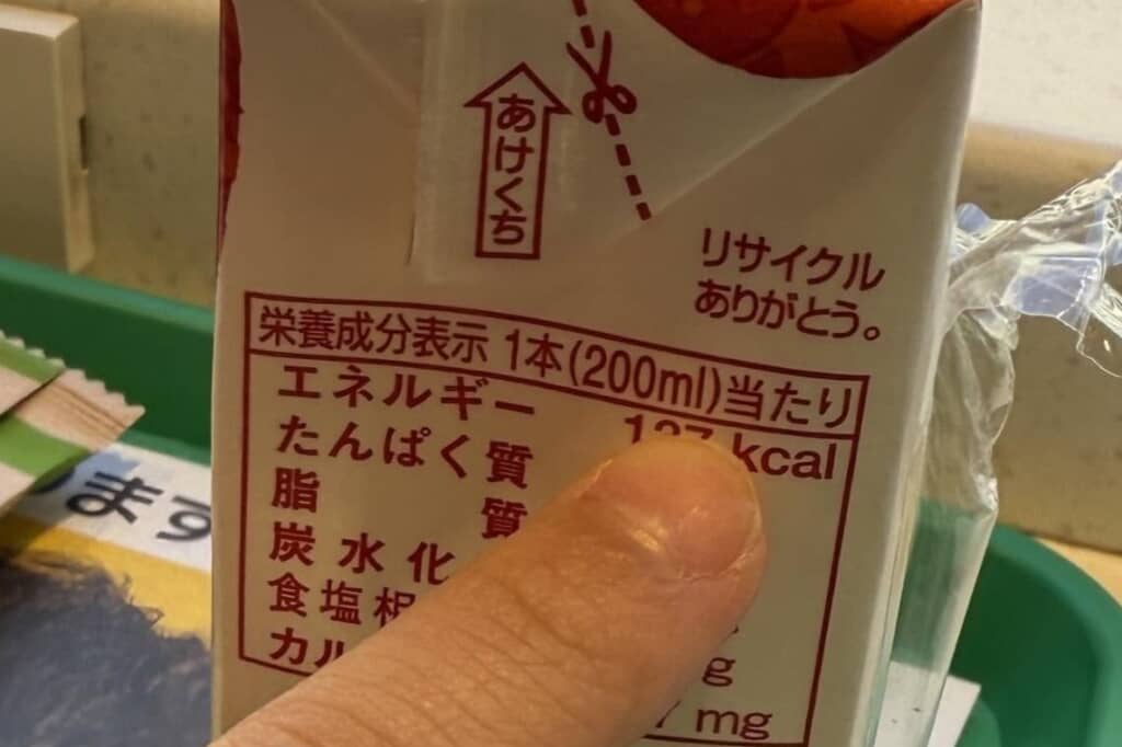 指先が「200ml当たり 137kcal」と書かれた栄養成分表示を指しているクローズアップ。