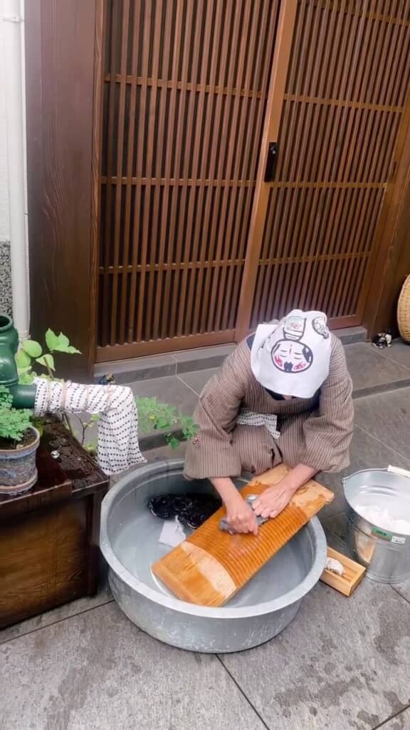 タライの水と洗濯板を使ってこすり洗いする様子
