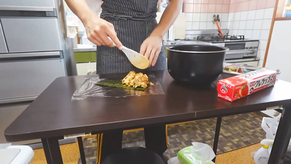 ラップの上で海苔にのせて握っていく