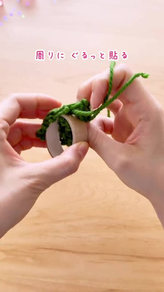 両面テープを貼ったテープ芯に毛糸の編み地を巻き付けている様子