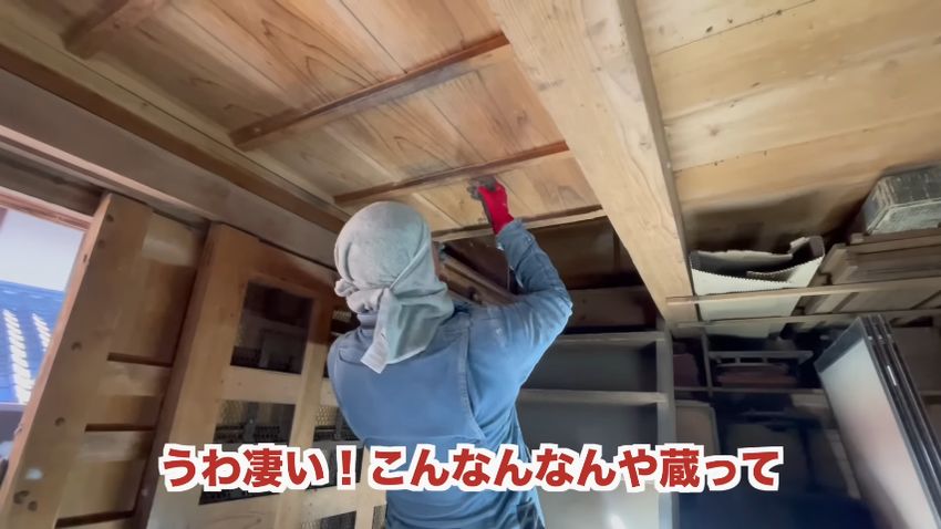 天井の板を動かして2階へ続く入り口を開ける様子