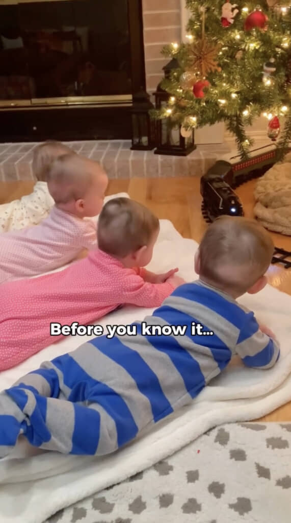 ツリーと機関車を眺める四つ子の赤ちゃん