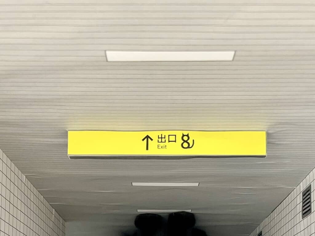 地下通路の天井にある黄色い「出口 Exit」表示板のクローズアップ