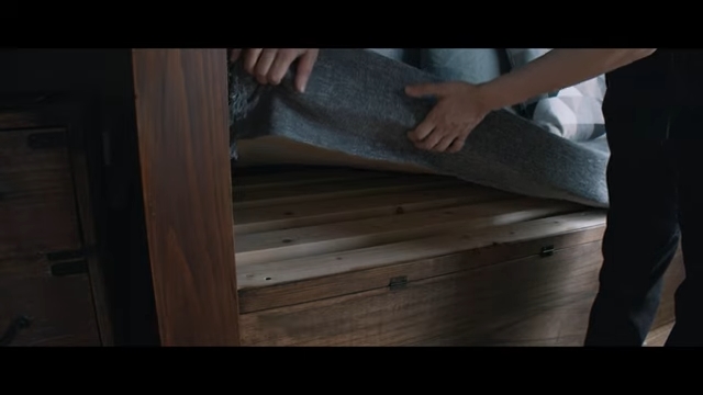 ベッドの骨組みにのせたマットレスをめくって見せている