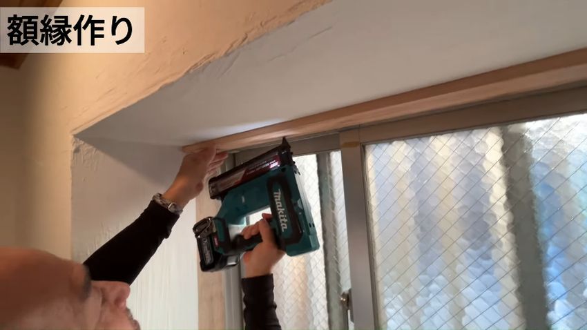 接着剤とクギで額縁を貼っていく様子