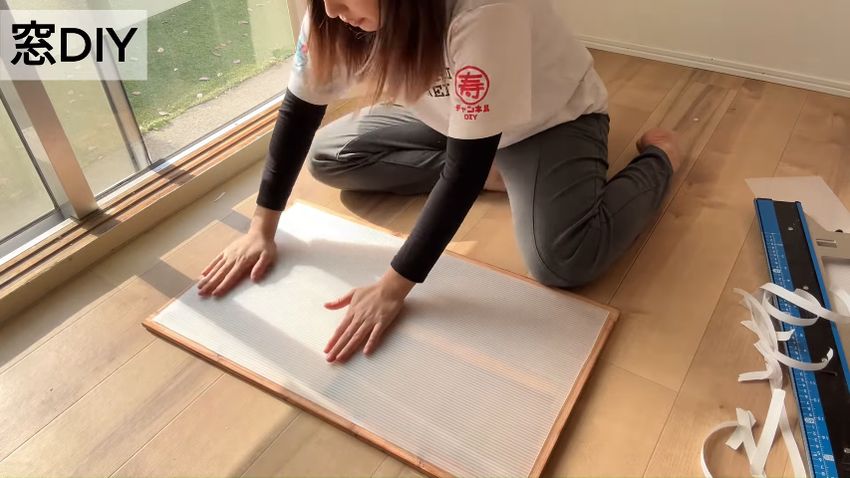 両面テープを貼った窓フレームに切り出したプラダンを貼り付ける様子