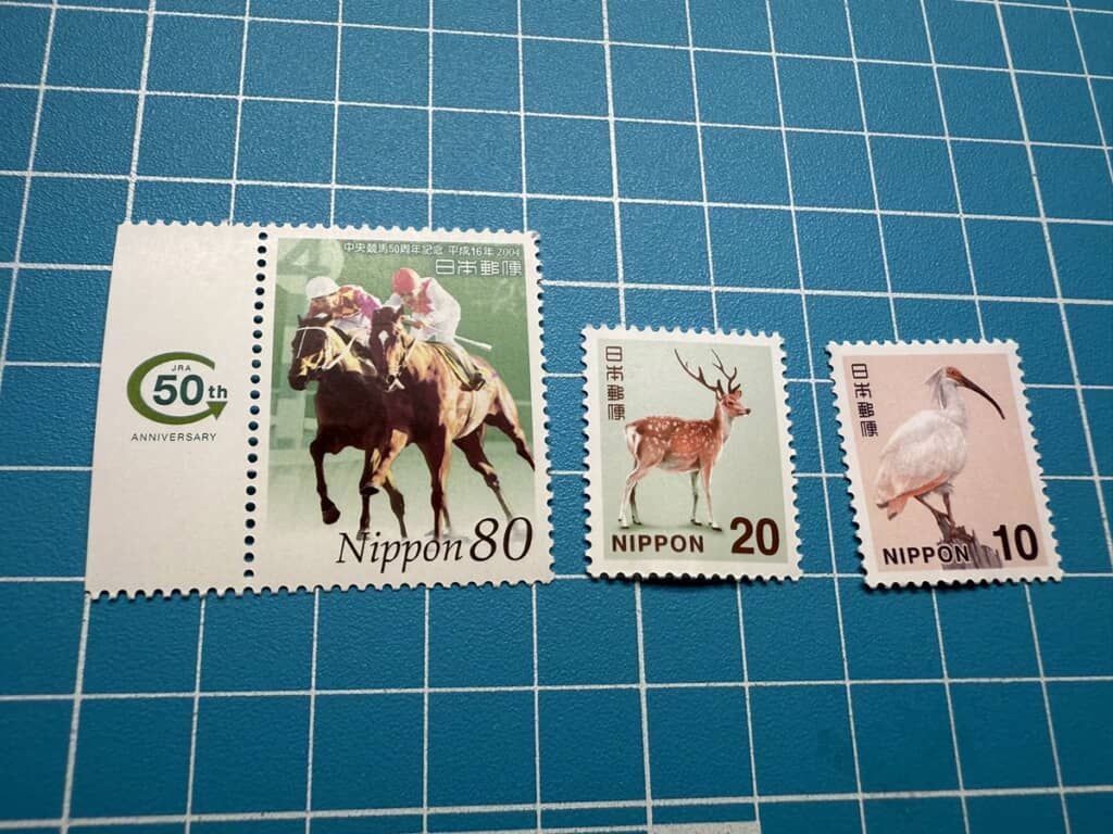 中央競馬50周年記念郵便切手とシカの切手、トキの切手を収めた写真
