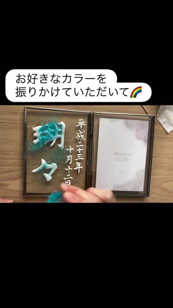 水色のパウダーを文字にかけている場面