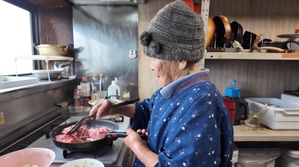 肉を炒める千代さん