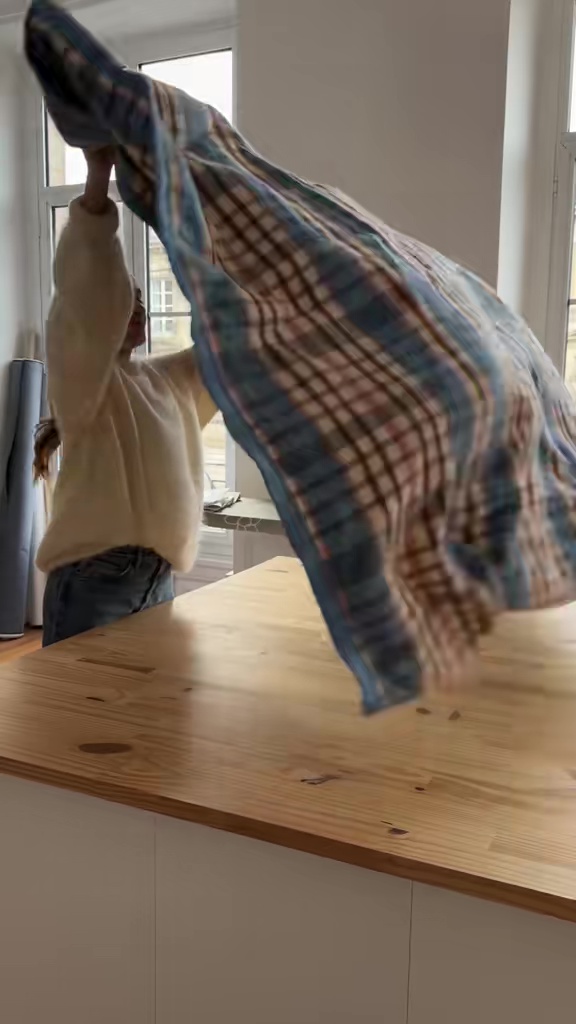 チェック柄の大きなブランケットを作業台に広げている様子