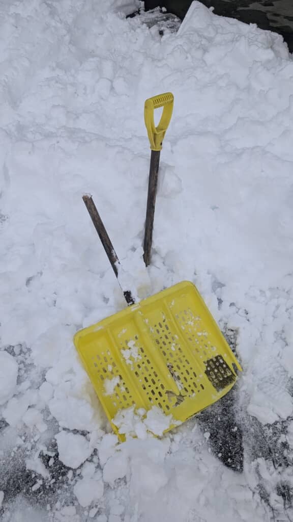 降り積もった大量の雪と柄の中心から折れたスコップ