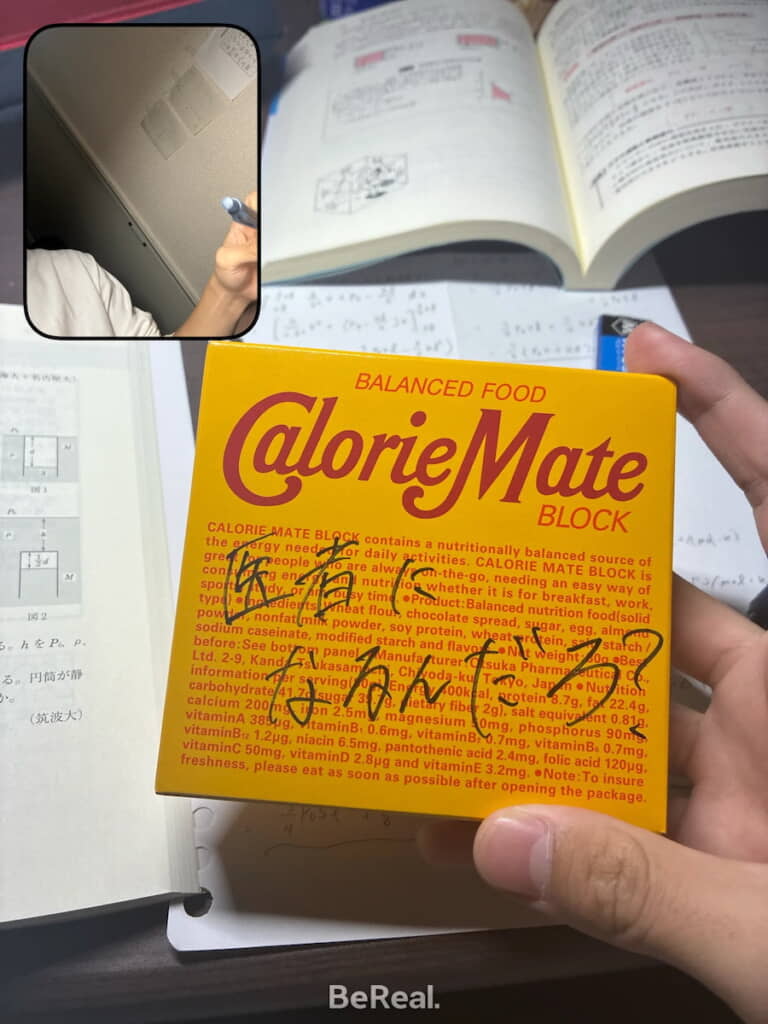 カロリーメイトの箱に胸熱メッセージ。インカメラ画像の手がペンを持っているのはタイムラグのため