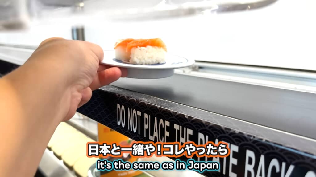 レーンから流れてきたサーモン寿司の皿を手に取る瞬間。