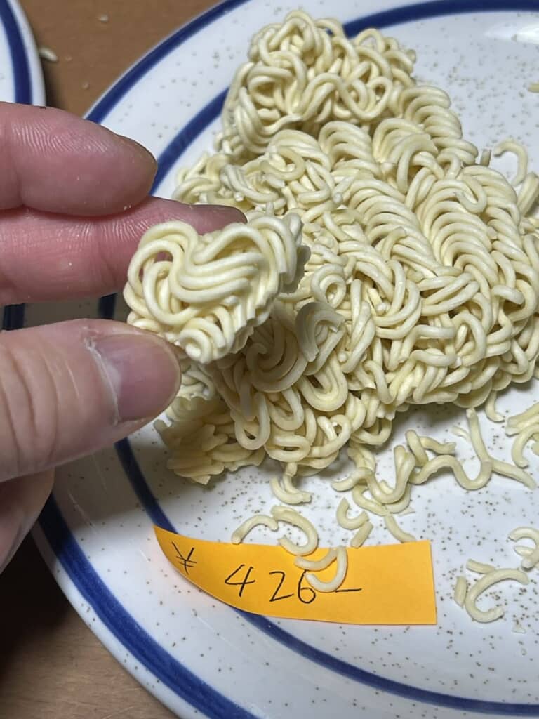 かたまり状のインスタント麺を指でつまむ様子