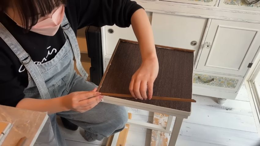 サイドテーブルの天板に枠を貼り付ける様子