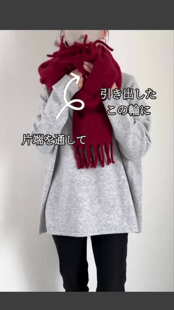 左側のマフラーを輪の内側から引き出し、右側のマフラーを通して