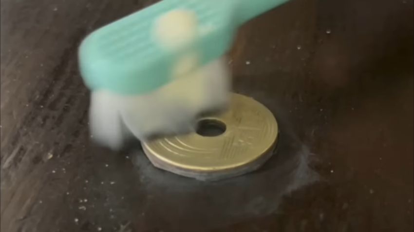 「クリームクレンザー重曹入り」を付けた「マイクロ極細歯ブラシ」で5円玉の表面を磨く様子