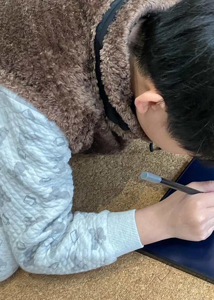 パジャマのままで熱心に何かを書く息子