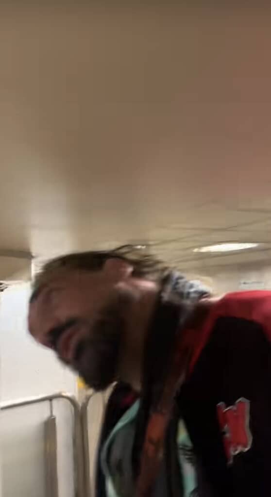 駅の通路で首を横に曲げながら歩く男性