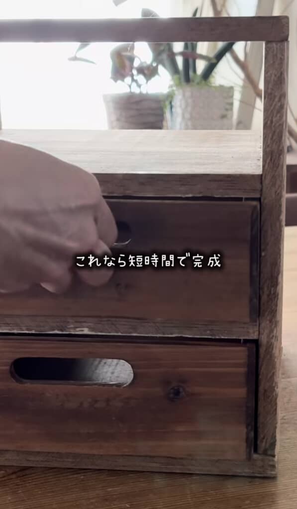 木製の小さな引き出しを手で開けている場面