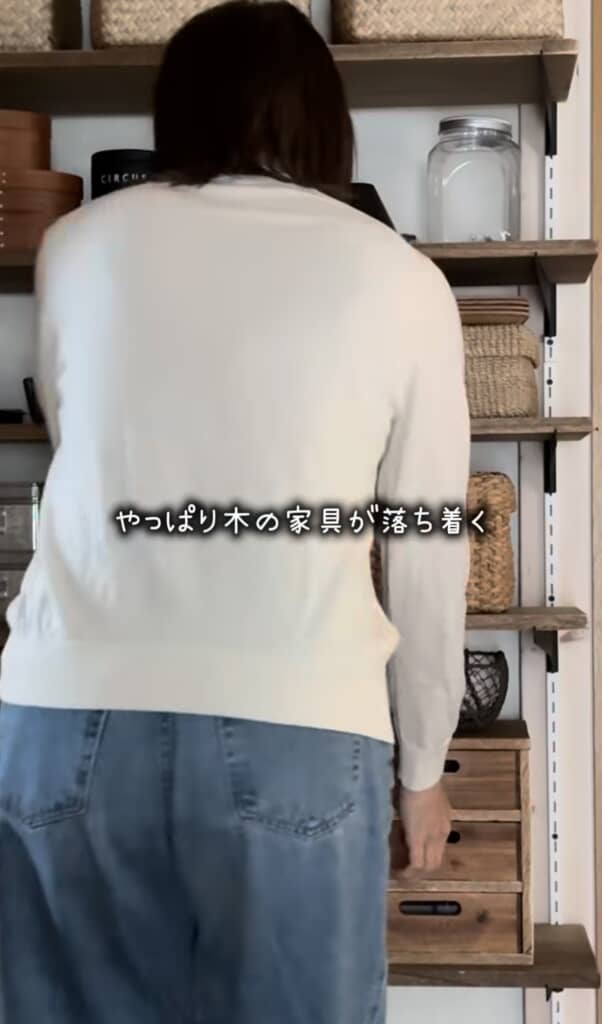 木製棚の前に立つ人とナチュラルな収納雑貨