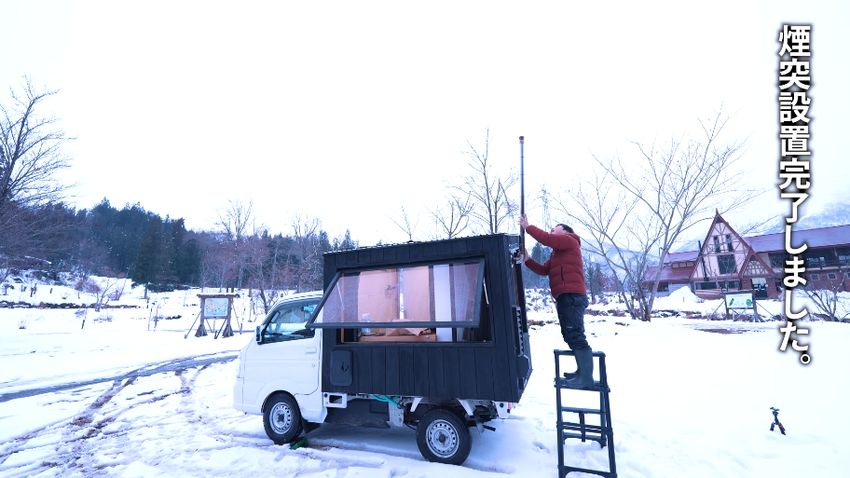 屋外で車体に煙突を取り付ける様子