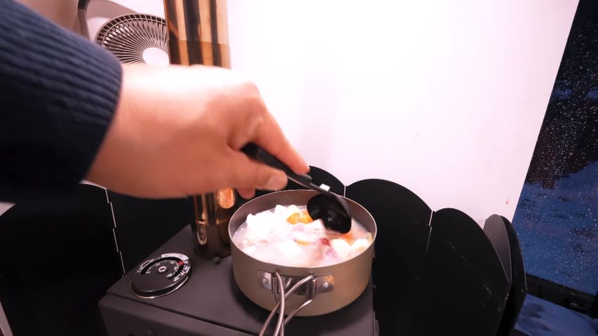 薪ストーブの上に鍋を乗せて食材を煮込む