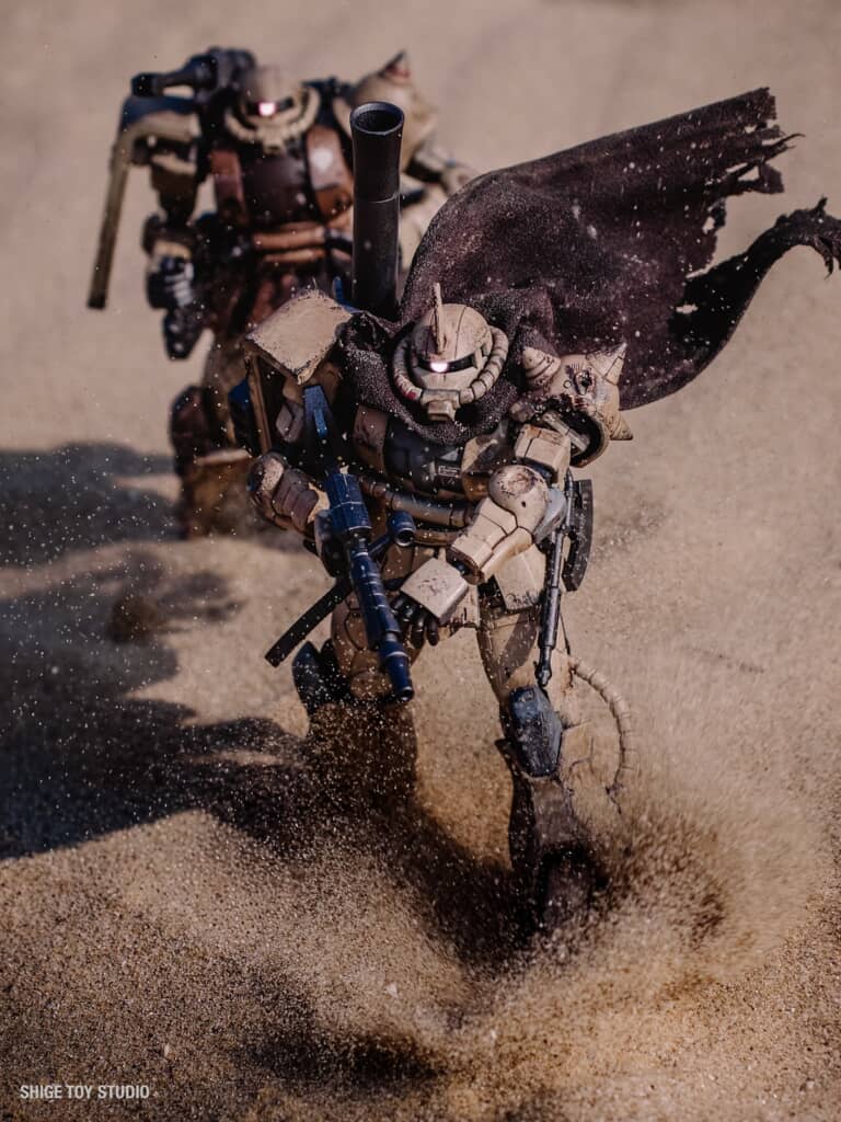 砂塵が舞う中、歩みを進める2機のザク