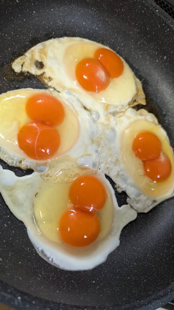 フライパンで焼かれた黄身が二つある目玉焼き