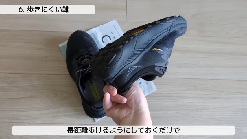 一組の靴のうち一足を持ち上げて傾けてソールを見せている