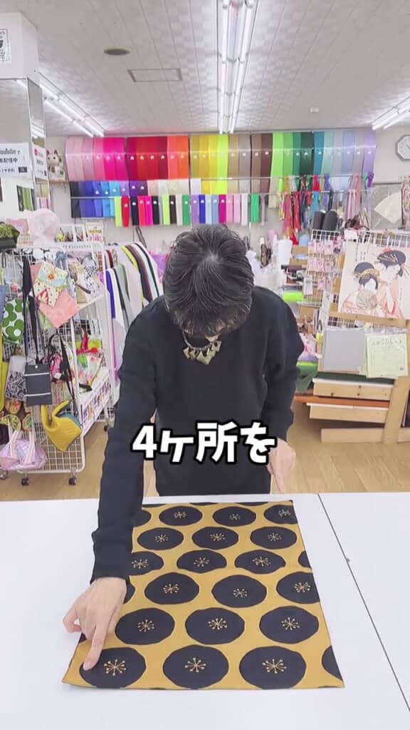 布の隅を指す人