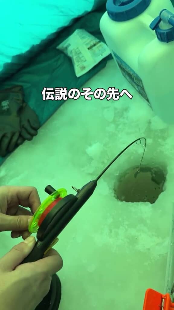 ワカサギ釣り用の小さな竿を氷に空けた穴へ垂らす様子