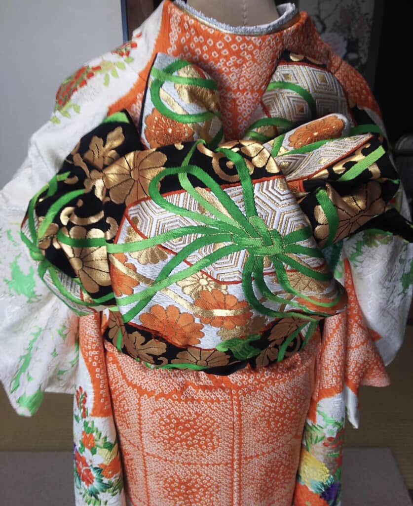 華やかな帯に鮮やかな緑の紐が描かれた帯