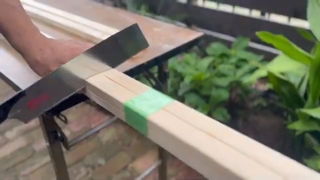 角材を縦2本横2本で組んで養生テープでとめてノコギリで切断している