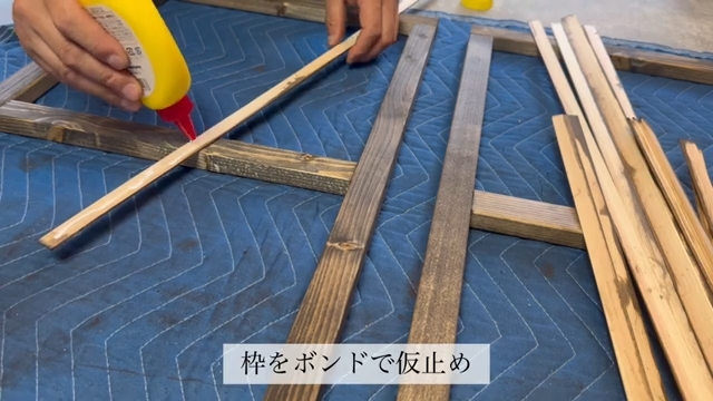 薄い桐加工材を窓枠にボンドで仮どめしている