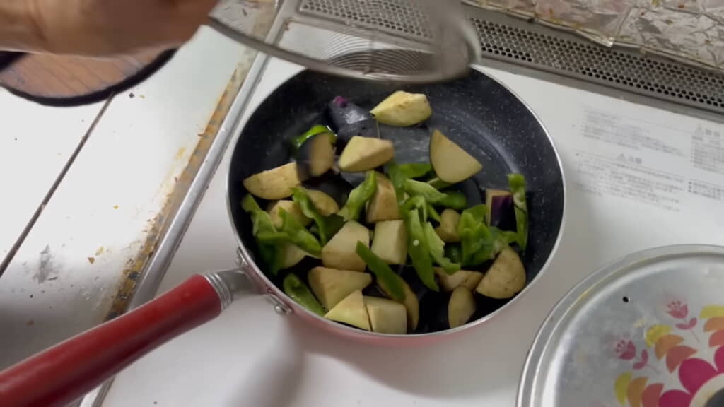 フライパンでナスとピーマンを炒める