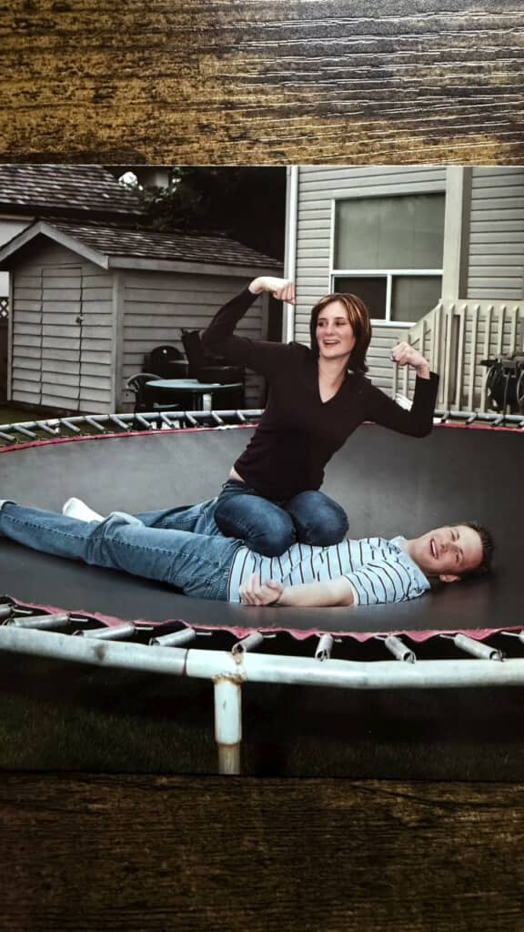 両親の婚約写真。トランポリンに寝そべる夫の上で妻は、夫のお腹に両膝を乗せ、ガッツポーズをしている。