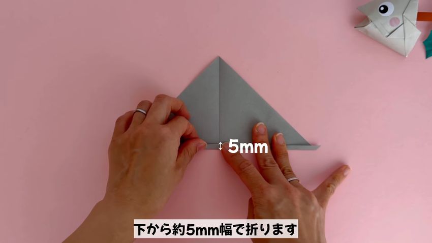 三角形にした折り紙の下端を約5ミリほど折る様子