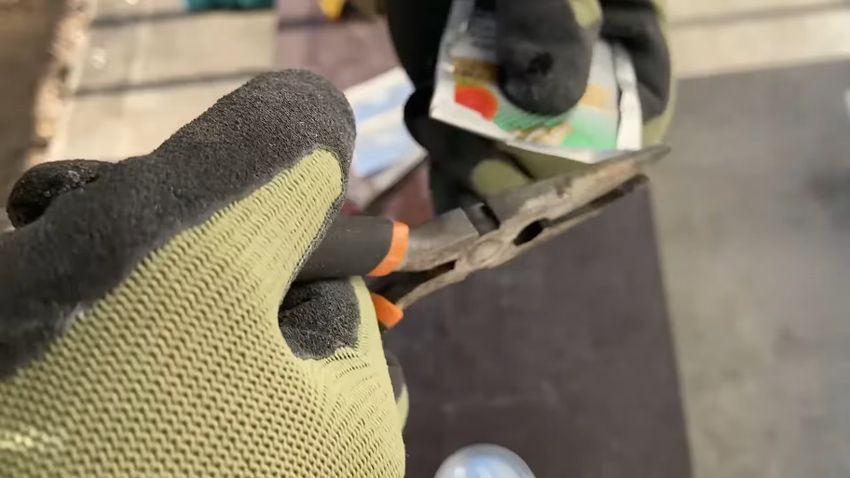 切り出したアルミ缶の端部をペンチで曲げる