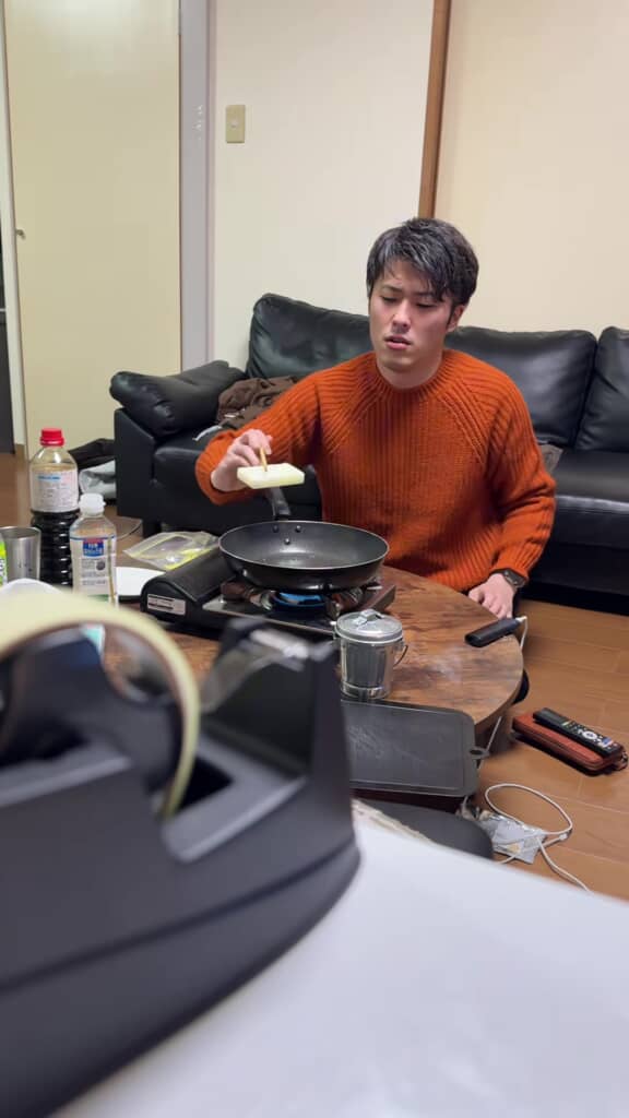 フライパンに“もち”を入れようと、箸でつまんでいる男性の姿