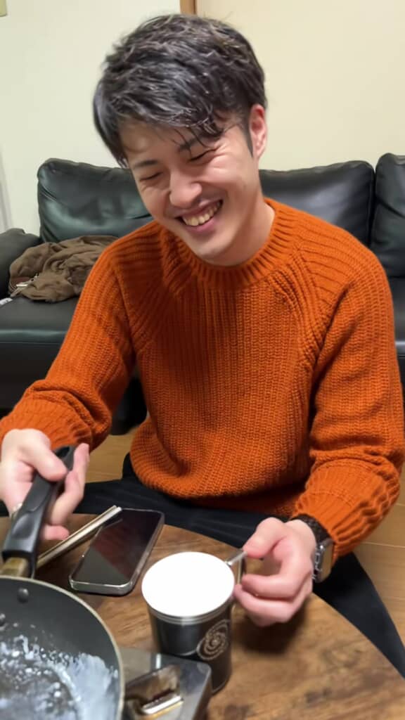 フライパンからコップへと、ホットミルクを注いだ男性