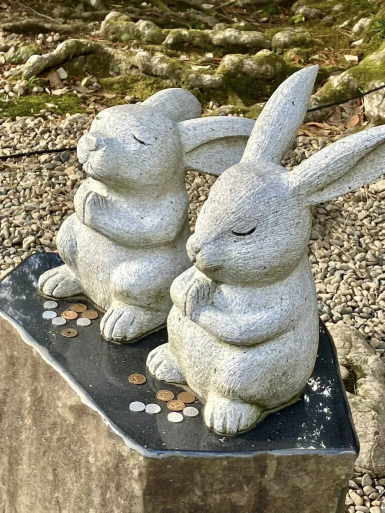 小銭が供えられた祈る姿のうさぎ石像