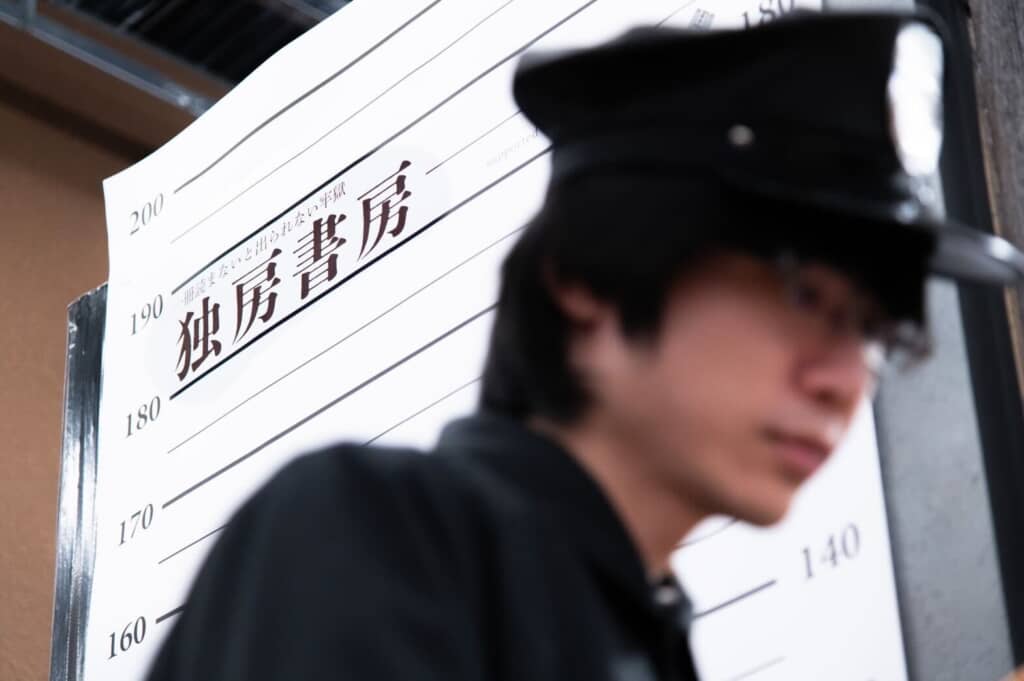 看守の後ろに記念撮影ができるポスターが写っている画像