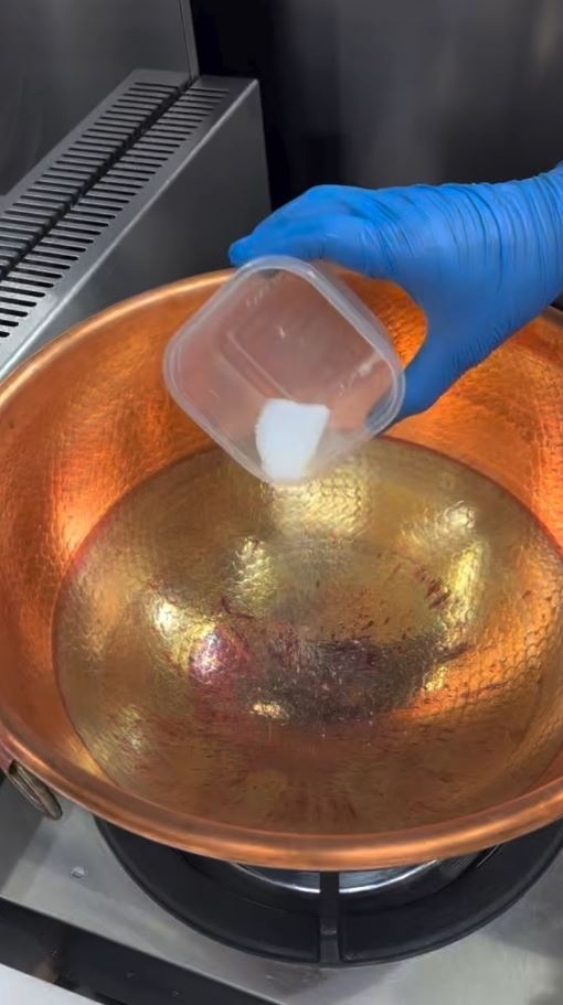 使い込んだ銅鍋に塩を入れる